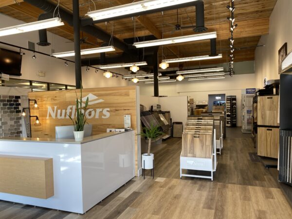 The front reception desk in the Nufloors Kamloops store, with wooden accents and flooring samples from various brands