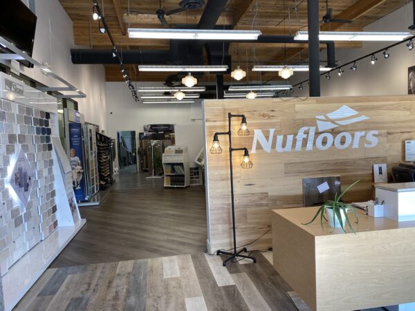 An interior view of the left side main area at Nufloors Kamloops, with the reception desk in the centre and flooring samples along the wall