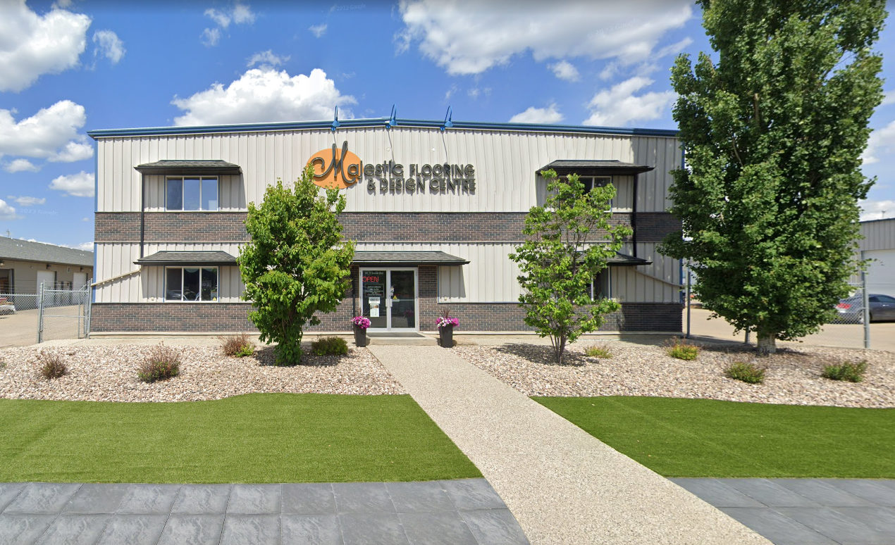 The exterior of the Majestic Nufloors Stony Plain flooring store in Alberta, showing the building entrance, landscaping, and a blue sky in the background