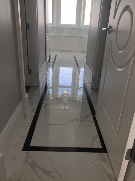 White and Black tiles on a floor reflecting the ceiling.
