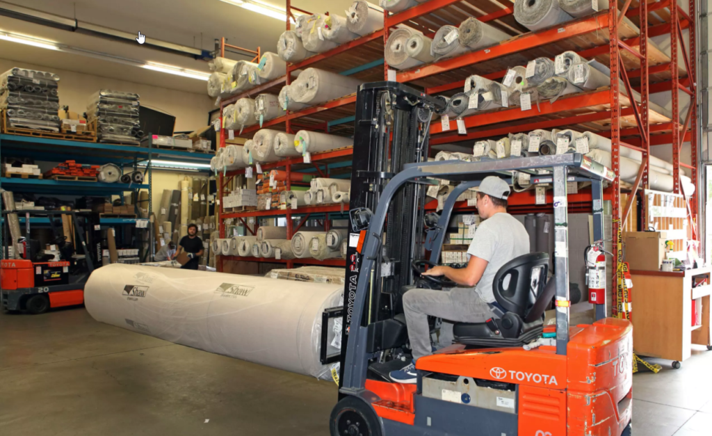 Forklift in a flooring warehouse lifting a roll of carpet