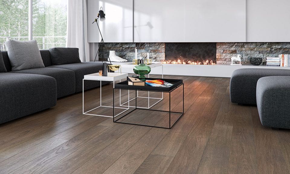 wide plank white oak hardwood flooring with a medium brown stain, featured in a modern living room with a large stone fireplace and grey sofas