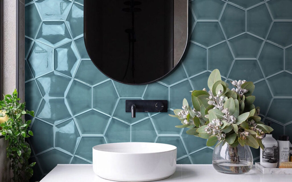 Turquoise geometric tiling behind a bathroom vanity, with a blackframed mirror and black tap over a white sink