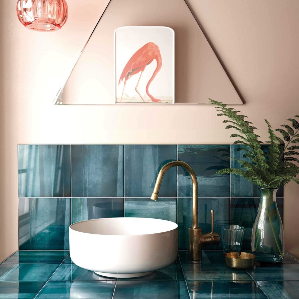 teal tile in a light pink bathroom with a gold tap and flamingo picture decor