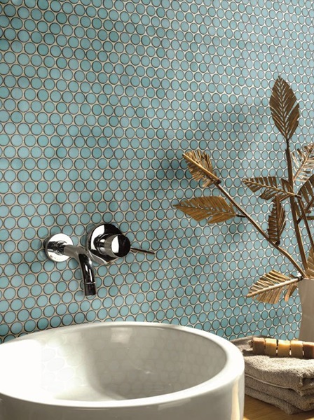 teal penny tile in a modern bathroom, shown behind a concrete sink, silver tap, and gold leaf decor