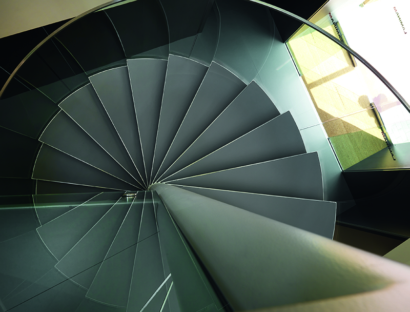 Grey tile flooring on a spiral staircase, top down view with a glass barrier