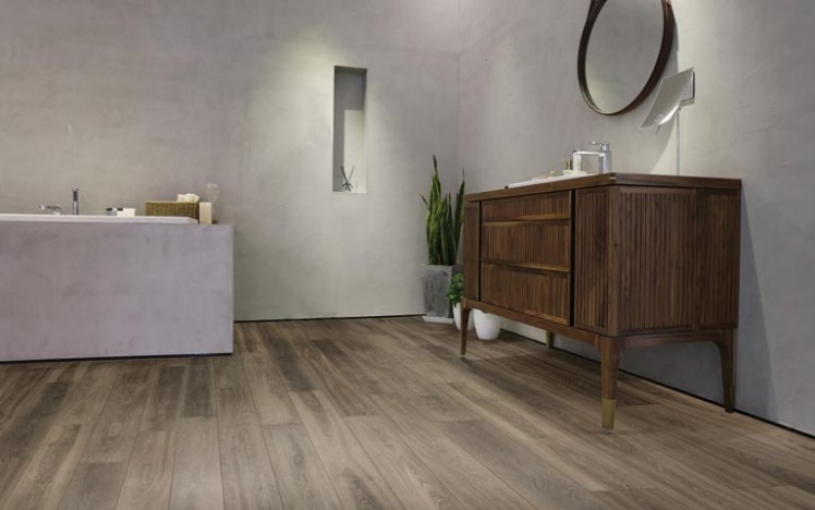 New Richmond Laminate flooring in a modern bathroom with concrete looking walls, a concrete tub and wood vanity. 