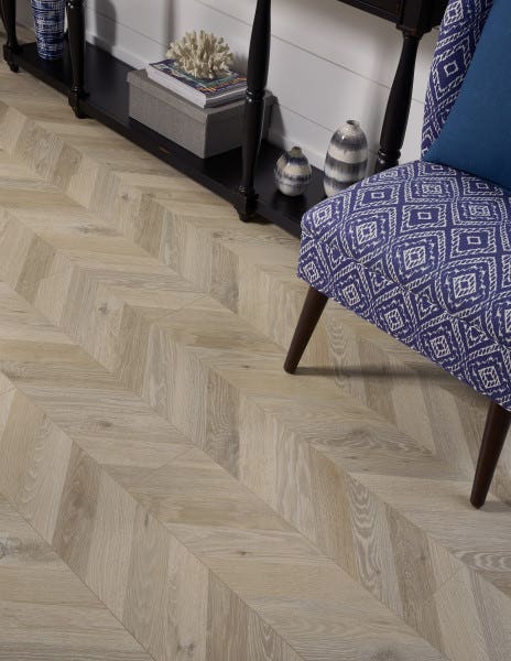 Bright diagonal wood patterned flooring in an entry way with a bold purple print chair and dark entry table