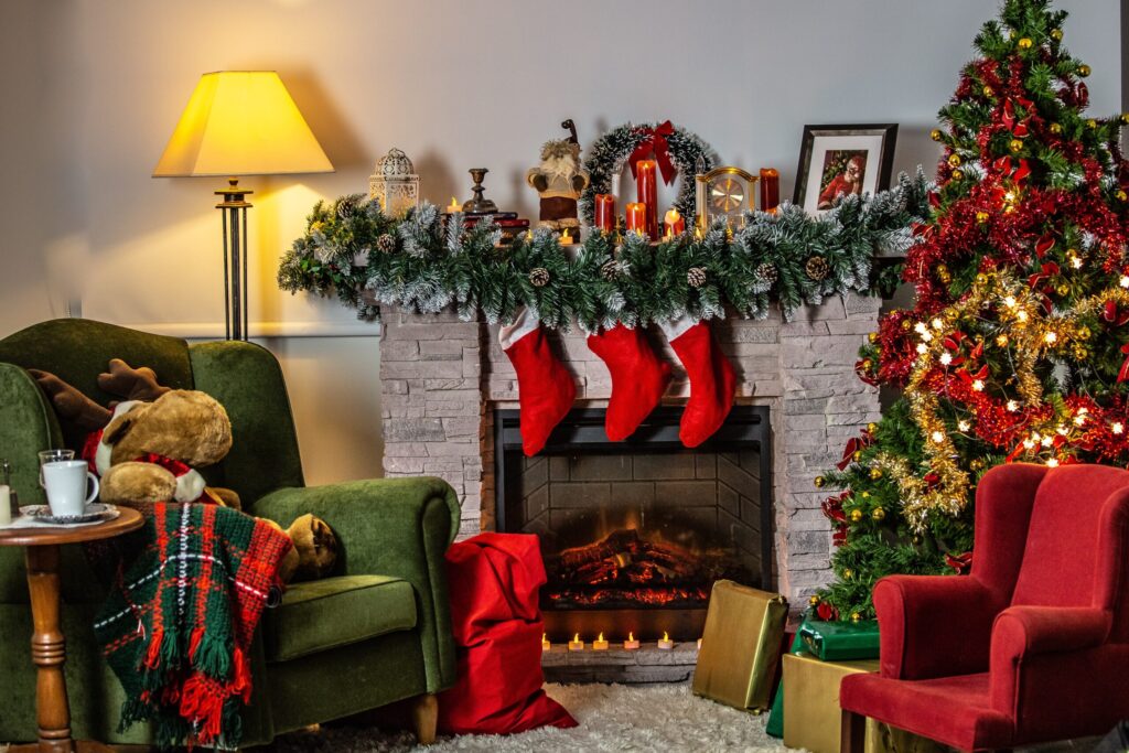 Festive decor in a living room, including green and red chairs, stockings hung on a fireplace and a christmas tree, highlighting christmas décor clean-up