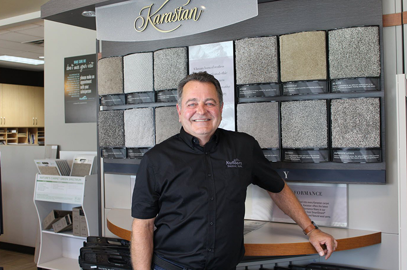 Headshot of Doug Cannell of Nuflooors Salmon Arm, a member of our local flooring group, standing in front of stone tile flooring samples