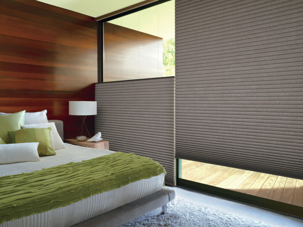 Honeycomb Blinds by Hunter Douglas in a bedroom, showcasing the first blind open at the top to hide the bed it's next to, and the second blind open on the bottom for extra privacy while letting light in. 