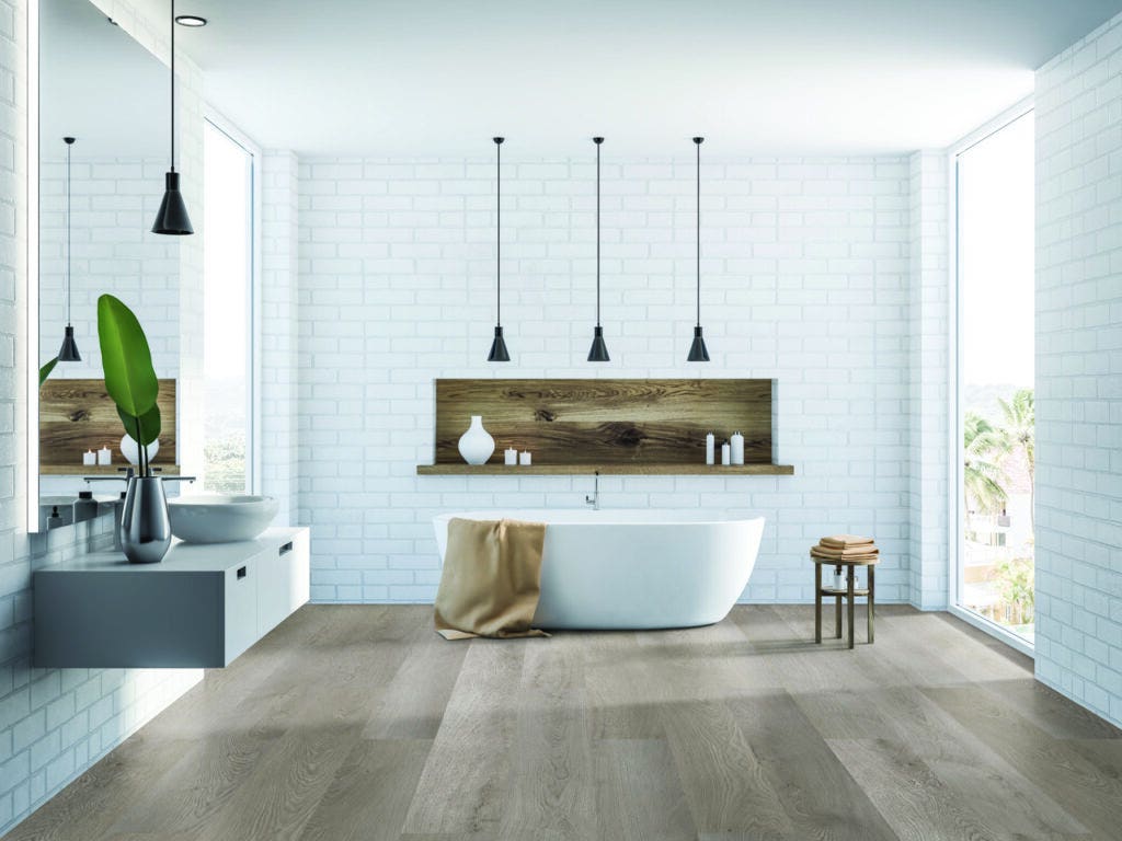 Gray Majestic Oak flooring by Wicanders, displayed in a modern bathroom with white subway tile on the walls and a white free-standing soaker tub