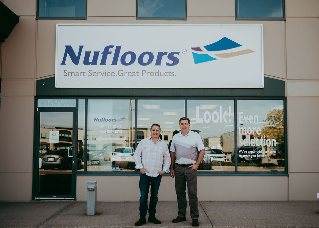 Nufloors Sherwood Park owners, Mark & Ralph, standing in front of their flooring store front with the Nufloors sign in the background.