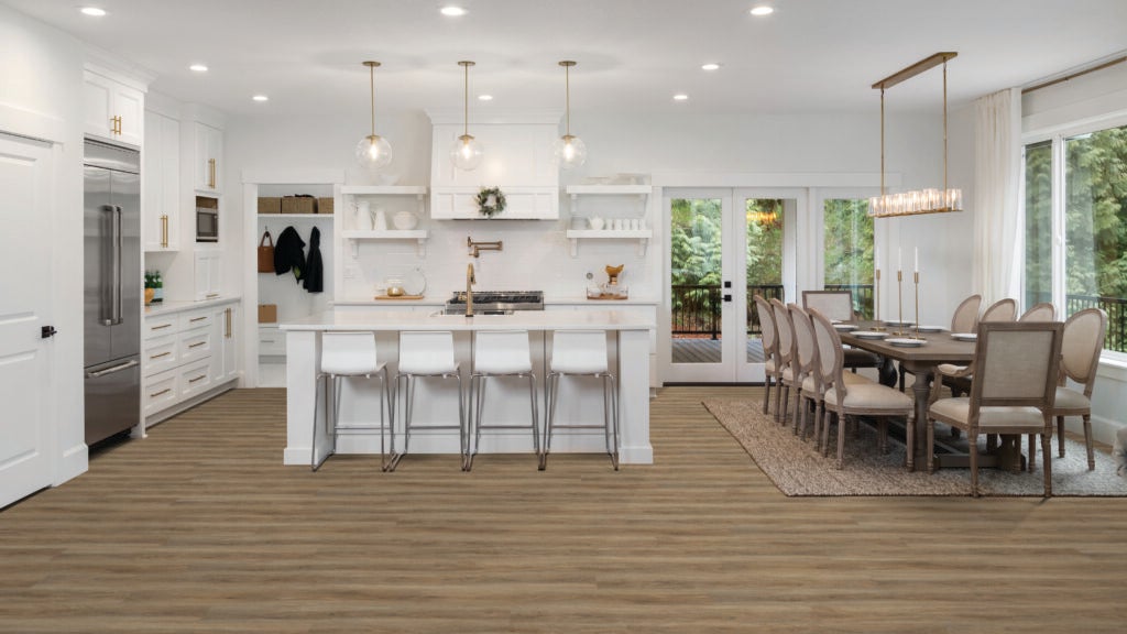 A open plan kitchen and dining room space with brown flooring, a white kitchen island, and light beige/brown dining room table and chairs, image source Beaulieu Canada.