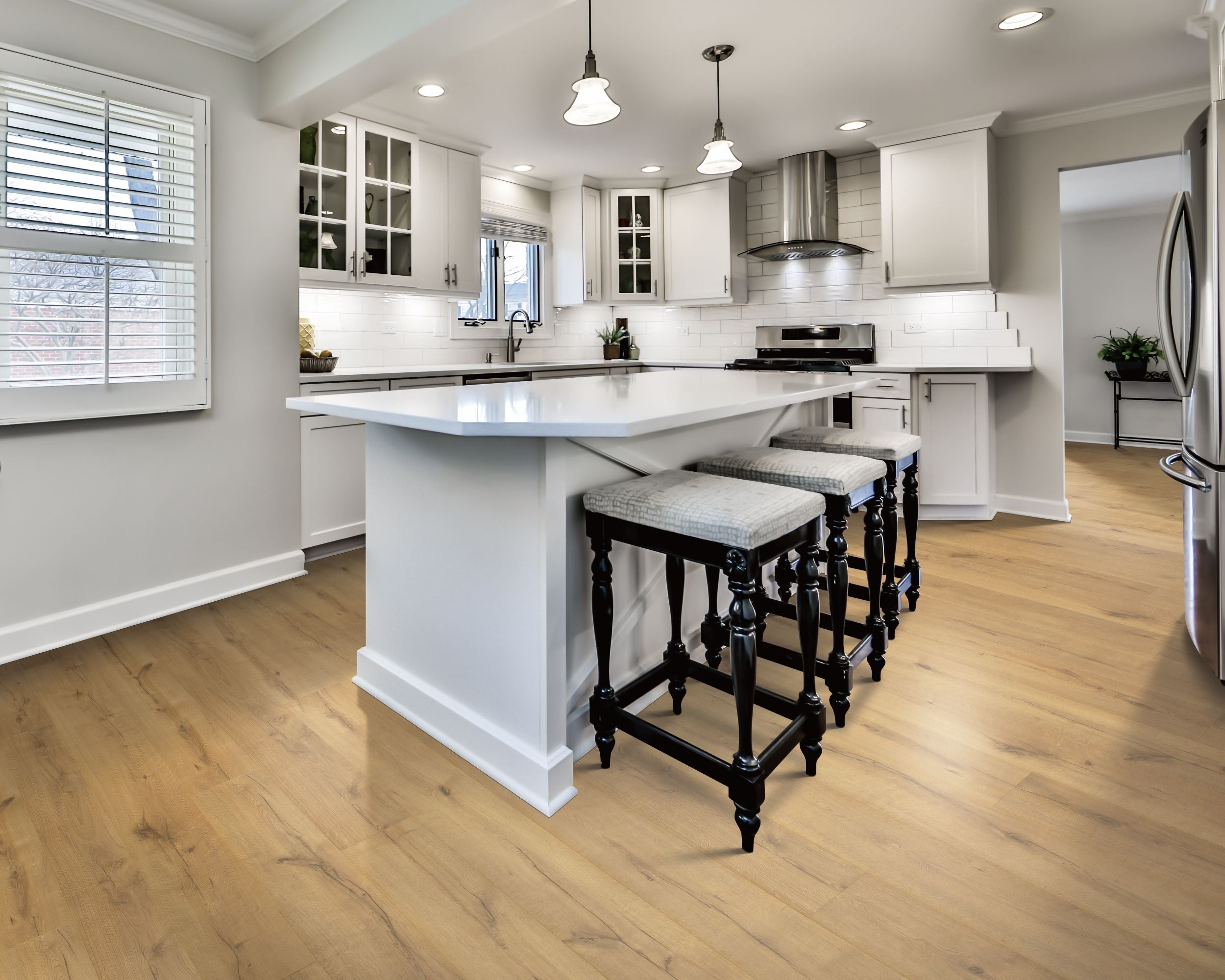 A pristine white kitchen with light brown flooring. A kitchen island is in the middle with stools lined up on the right side, image source Mohawk Floors