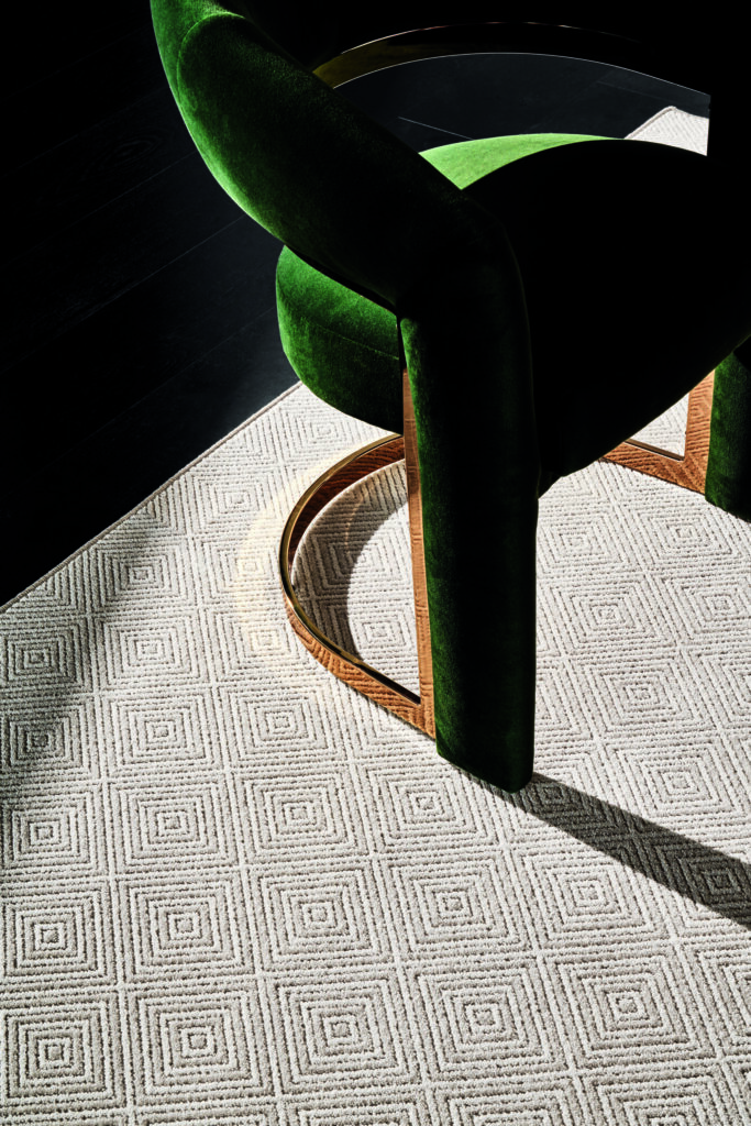 Beige area rug with geometric diamond pattern on a black floor.