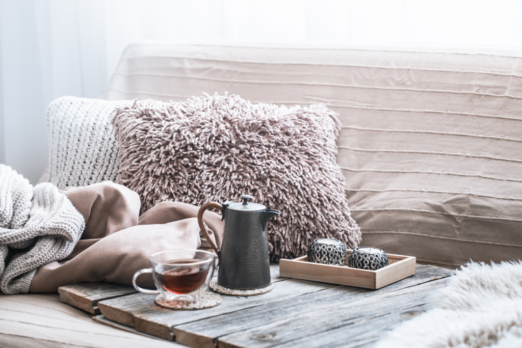 Bed with rustic wooden tray and cup of tea, fuzzy pillows and blankets that will keep you warm in the fall.