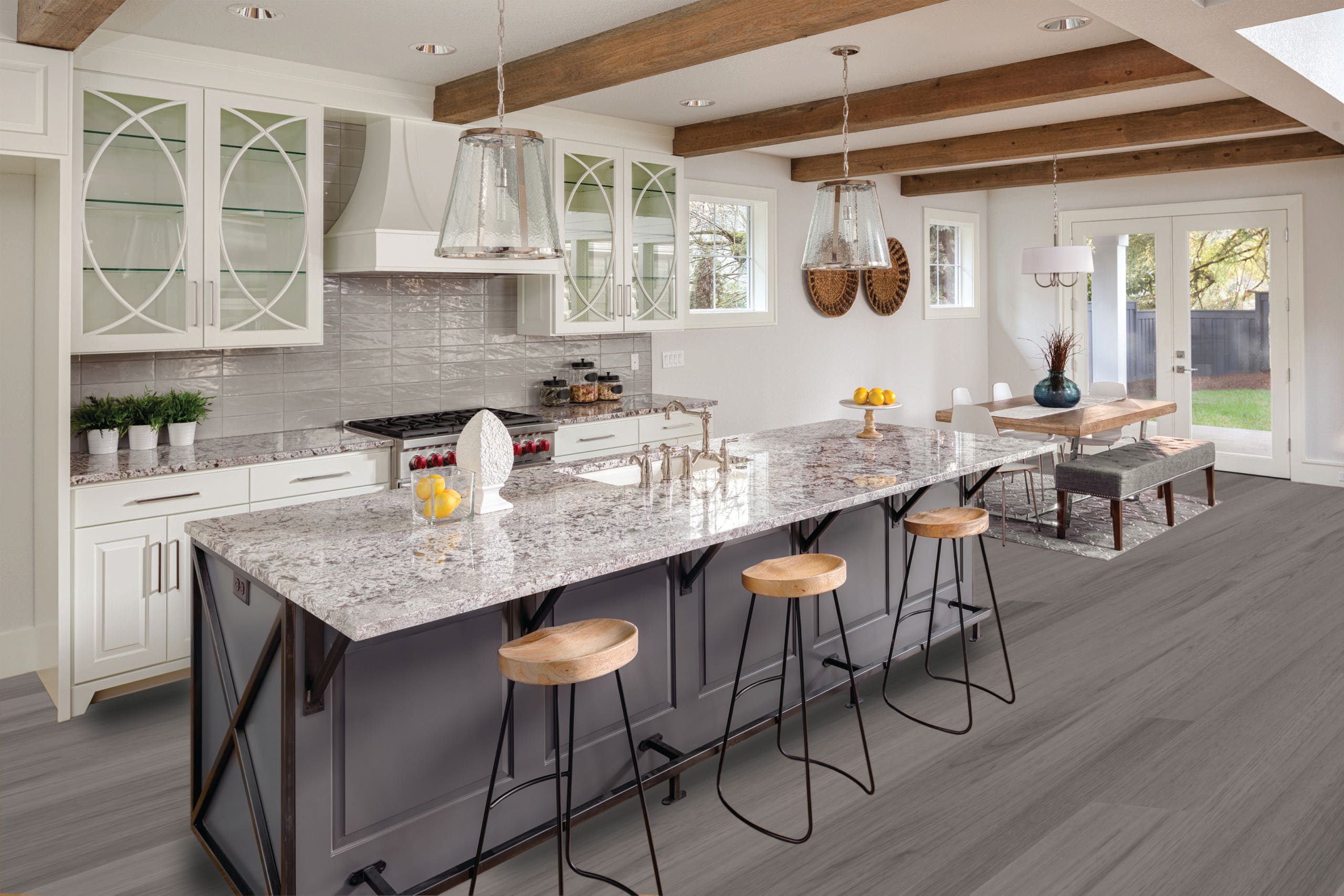 Beautiful kitchen with lights off in new luxury home with island, pendant lights, and glass fronted cabinets, and view of dining room.