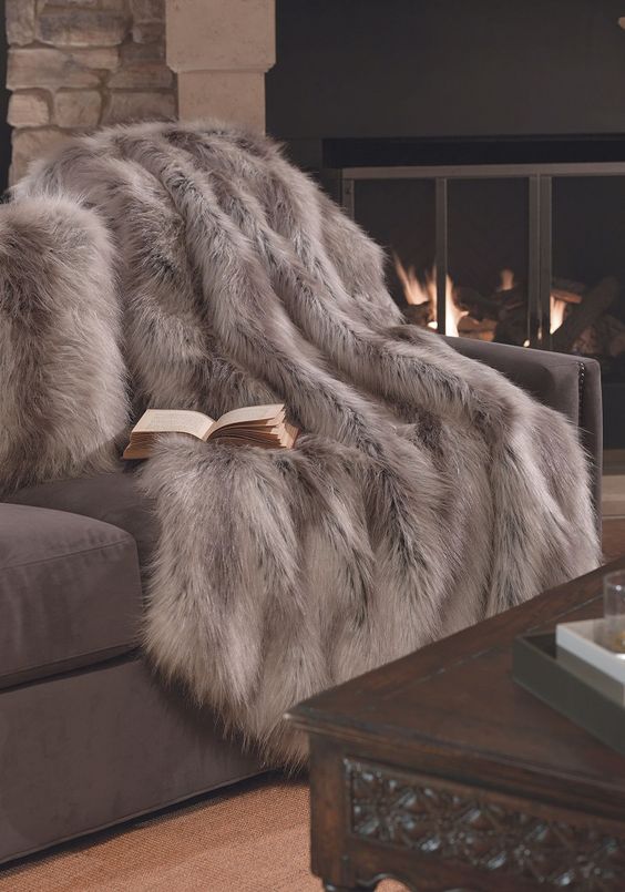 Faux fur throw on couch next to fireplace.