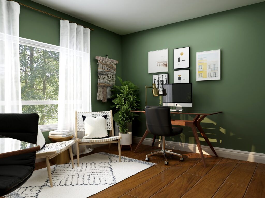 Home office space with 2 desks, green walls and accent chairs.