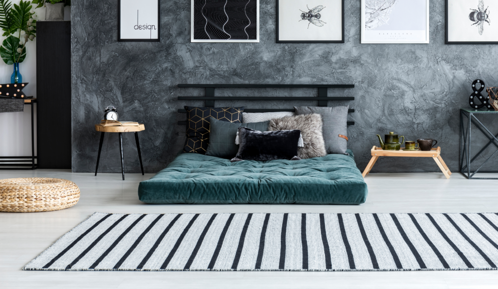 Art deco style bedroom with white laminate floors, a black and white striped rug, and black and grey marbled wall.