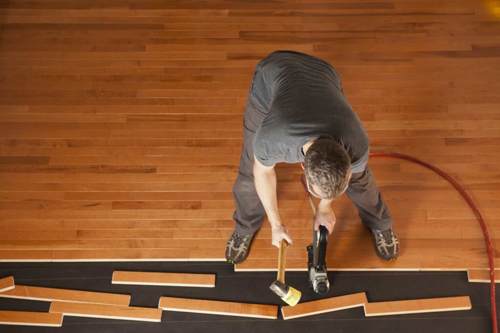 Top view of a man installing planks of hardwood floor.