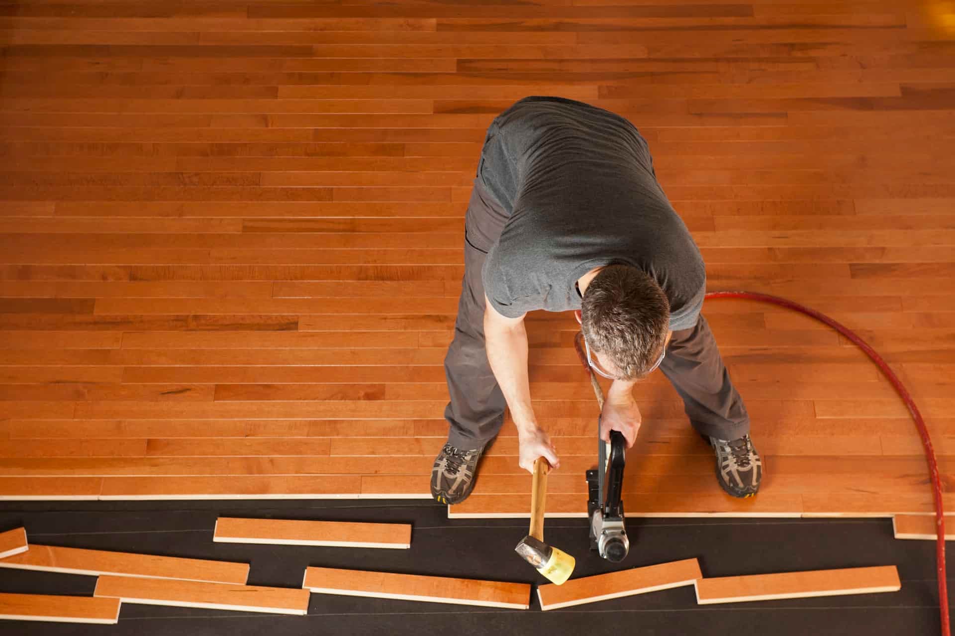 Top view of a man installing planks of hardwood floor