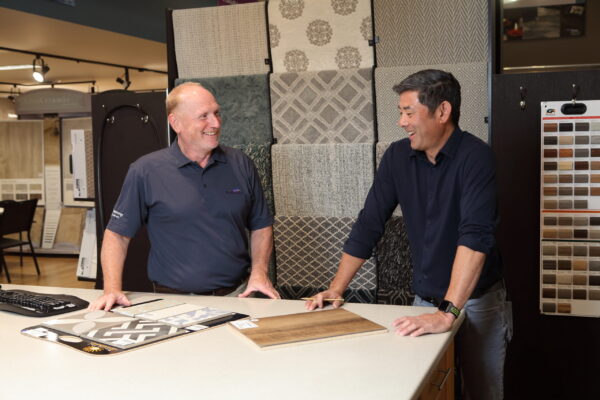 Vernon Nufloors Team Member Helping a Customer Look at Flooring Sample