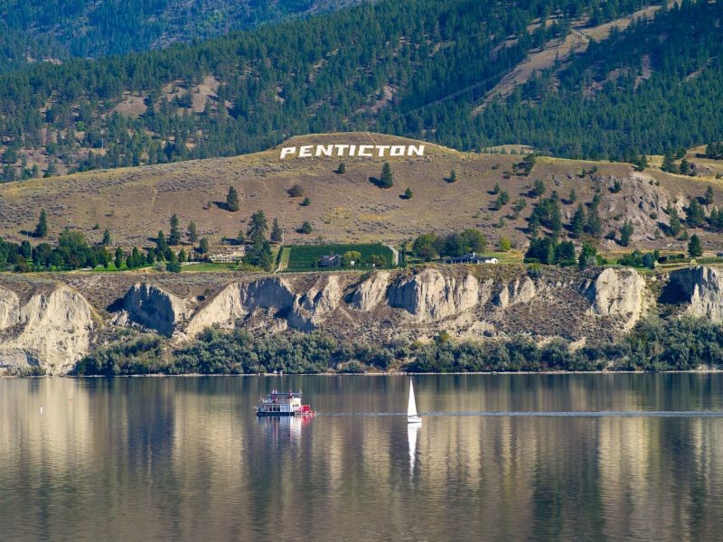 Lake and Hillside with Penticton sign on side of the mountain