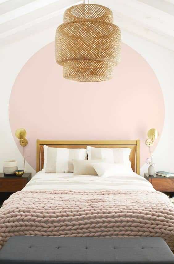 Bedroom with large pink dot behind bed, pink chunky knit throw on bed and wicker light fixture; relating to painting that was done as part of a spring update.