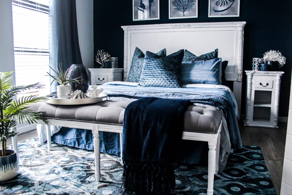 Room with dark blue accent wall, painted white classic-style furniture, large blue area rug and blue and grey decor accents throughout.