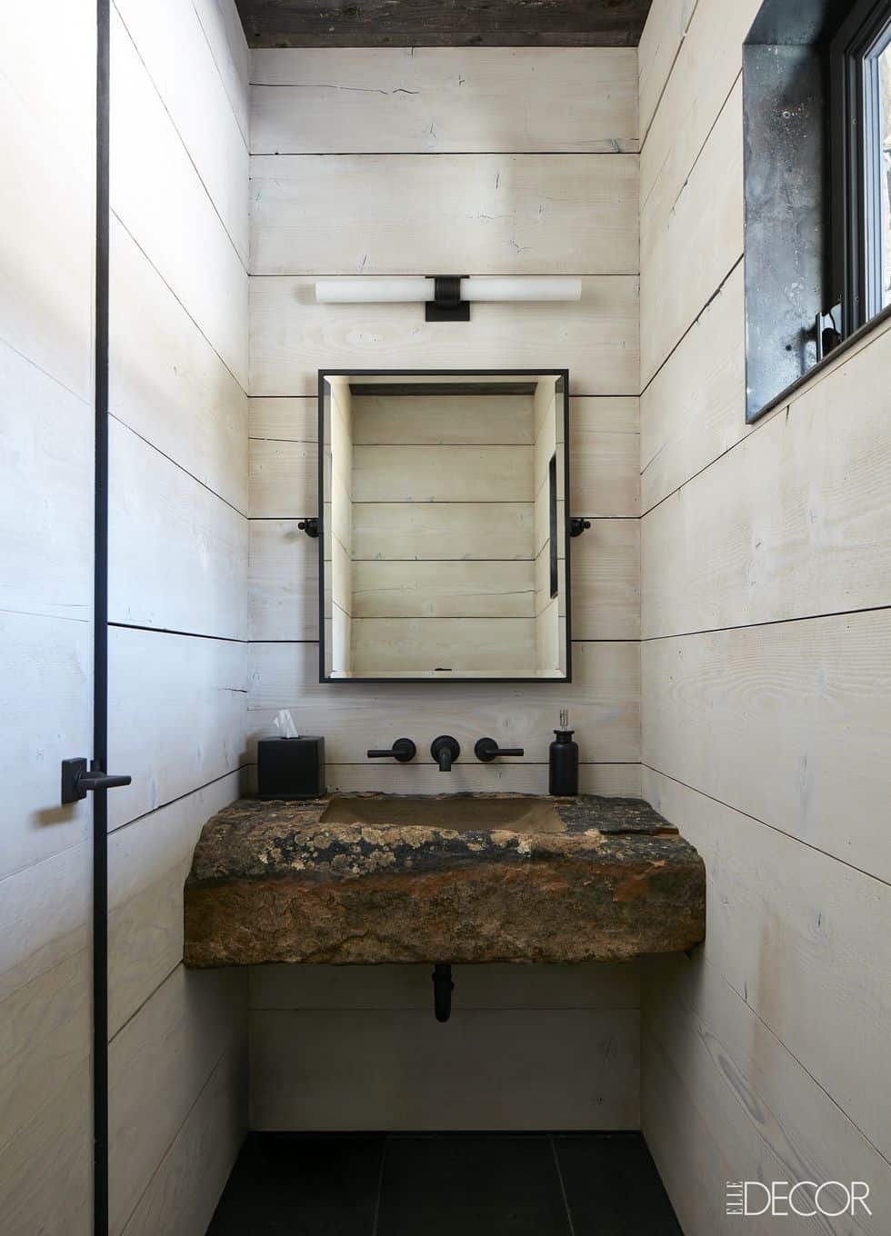 Bathroom with wooden walls and a raw natural stone sink.